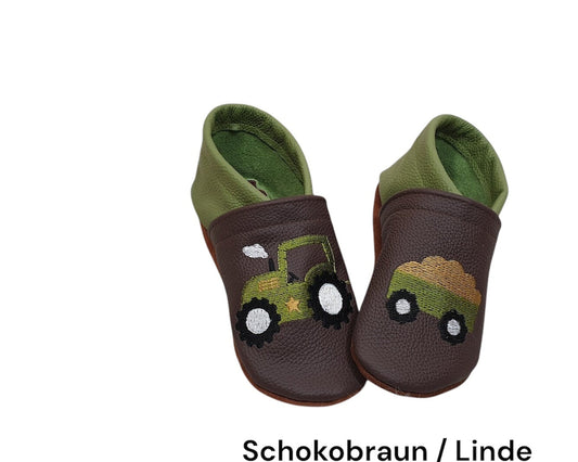 Lederpuschen für Kinder in Schokobraun und Linde mit farbenfrohem Trecker-Motiv und Anhänger, gefertigt aus hochwertigem Ökoleder und auf Wunsch personalisierbar.