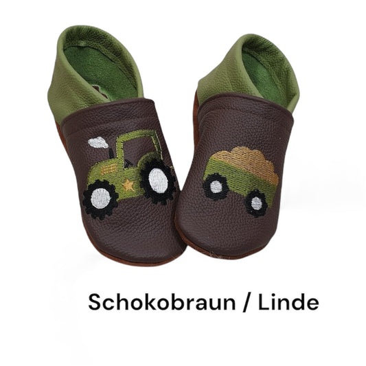 Lederpuschen für Kinder in Schokobraun und Linde mit farbenfrohem Trecker-Motiv und Anhänger, gefertigt aus hochwertigem Ökoleder und auf Wunsch personalisierbar.