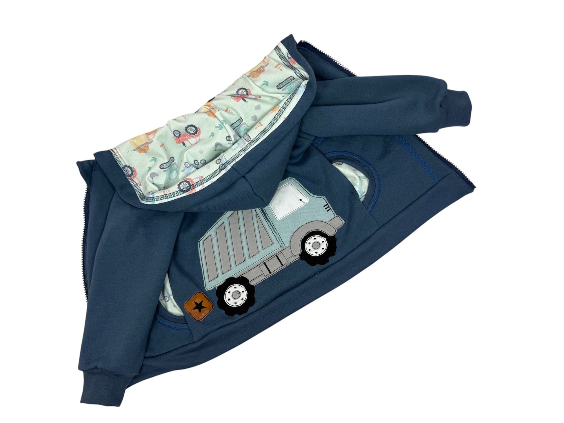 Handgemachte blaue Sweatjacke für Kinder aus Softsweat, gefüttert mit Mini-Trucks Jersey in Aquarellgrün. LKW Stickerei auf der Rückseite, ideal als Übergangsjacke für Jungen